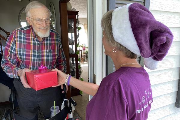 Senior man receiving holiday present from BASTAS volunteer.