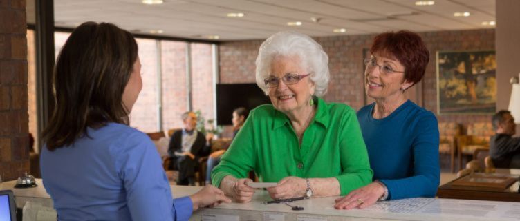 caregiver assisting a senior check in a doctors office