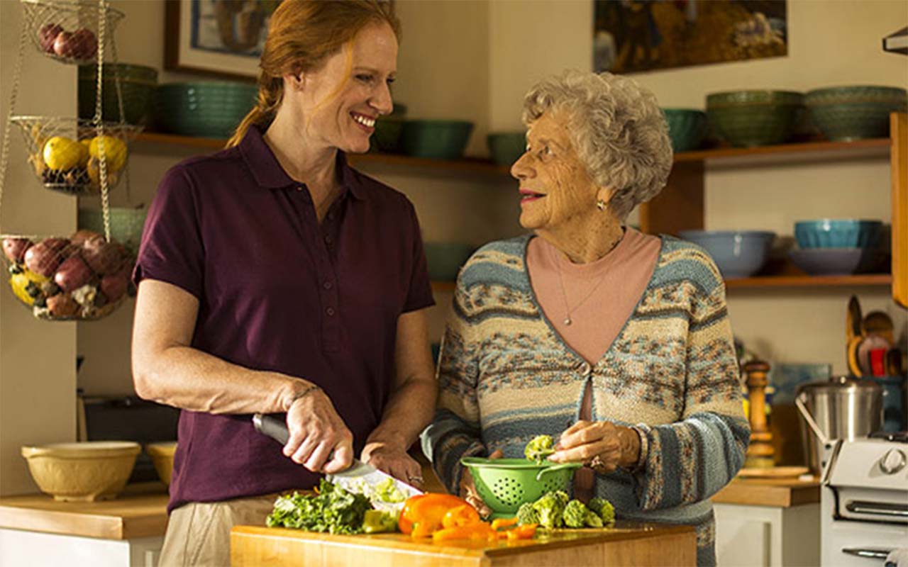Caregiver and Senior preparing meals and having a good time