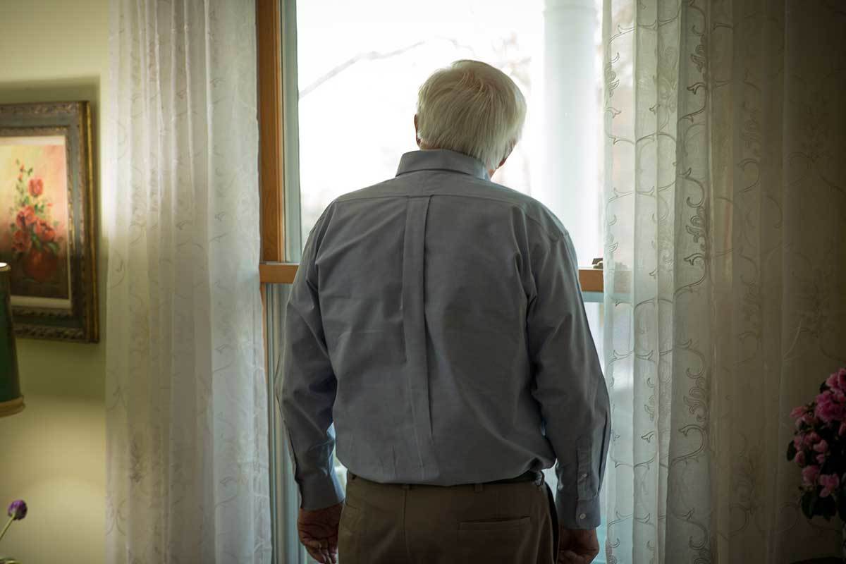 Older man looking out window