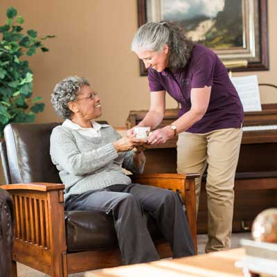 Caregiver bringing tea to a senior