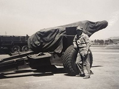 old photo of soldier leaning on army equipment trailer