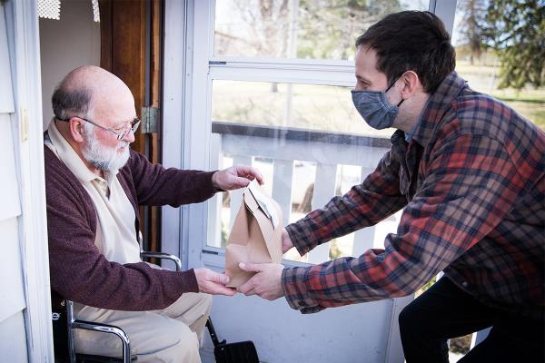 Gentleman delivering sack lunch to older man