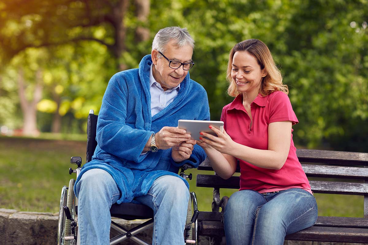Caregiver helping a senior to use a tablet