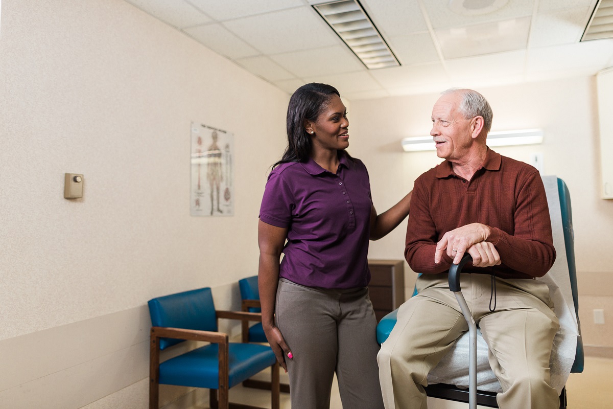 A senior man with can sits in doctor office examination room