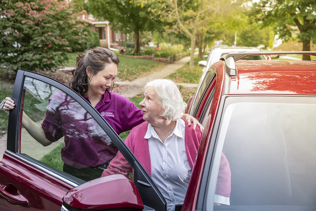 Caregiver helping a senior woman out of a car