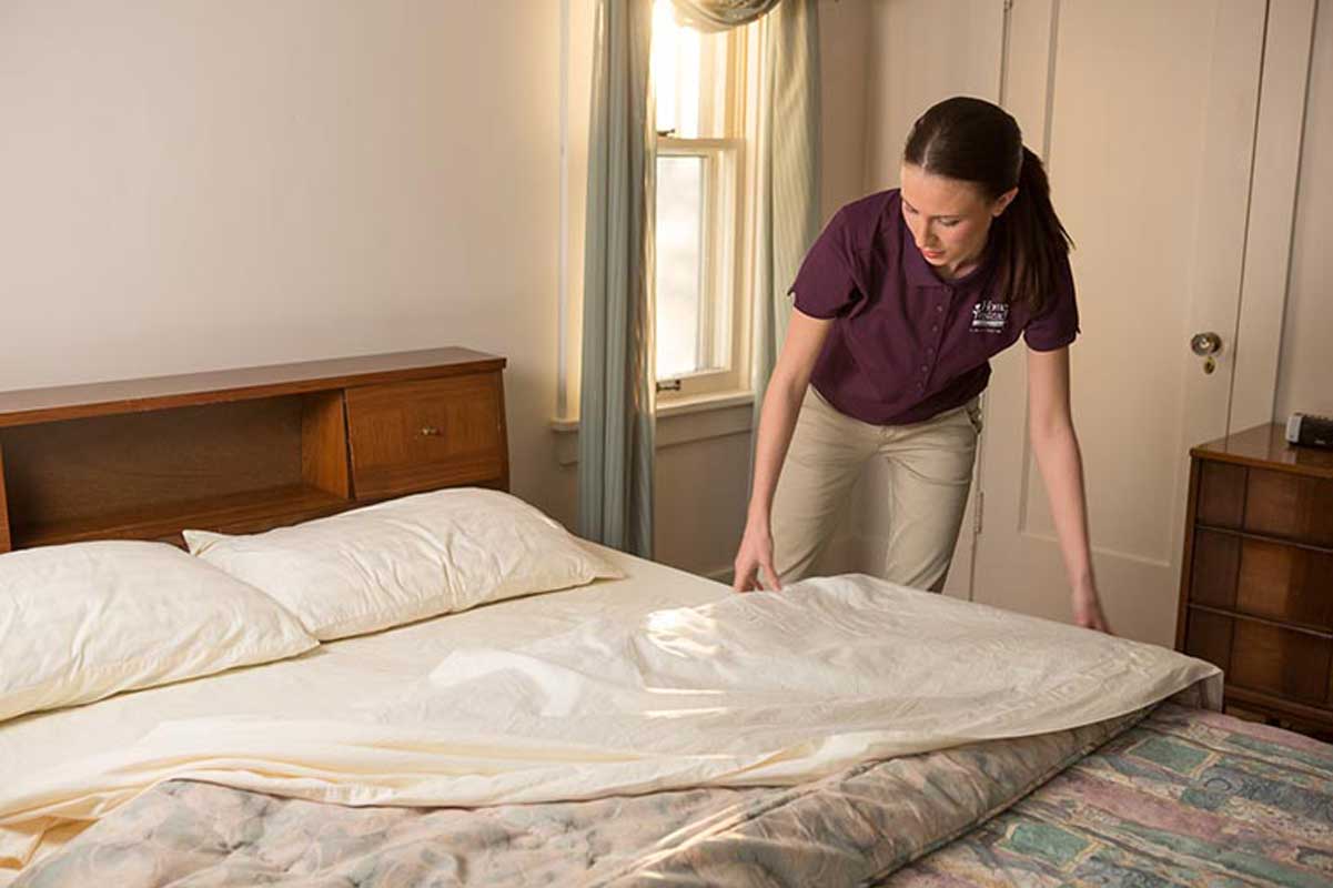 A Home Instead caregiver making the bed