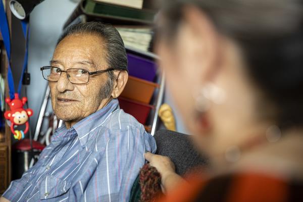 Senior man with glasses talks with caregiver