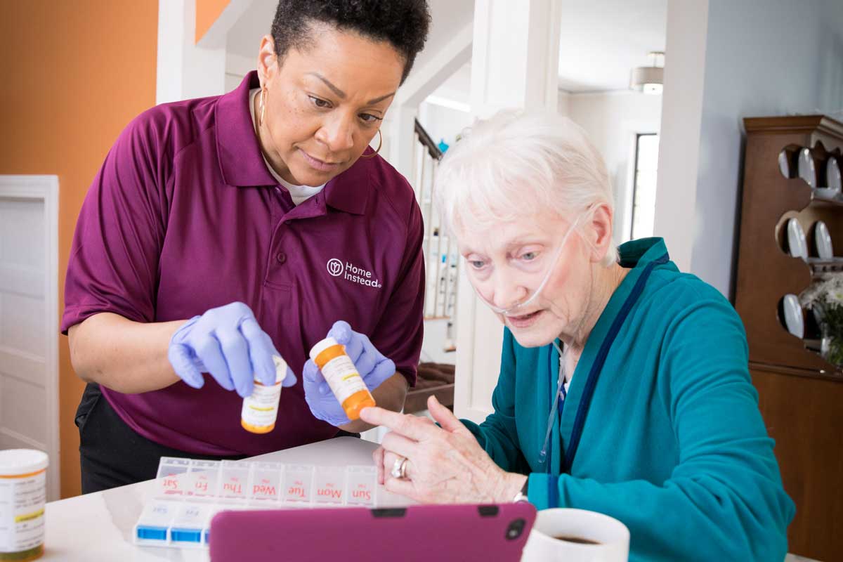 A Homeinstead caregiver is helping a senior with medication reminders