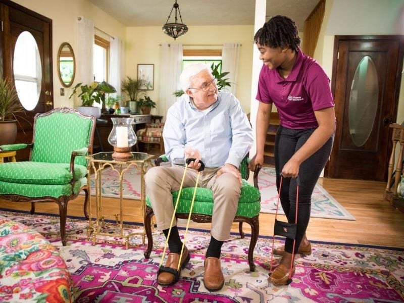 home instead caregiver cheerfully assisting senior client transition to home care