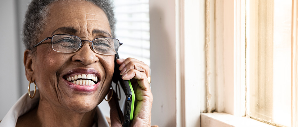 Senior woman smiles while talking on mobile phone at home