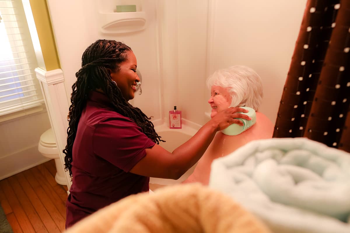 Caregiver helping elderly woman bathe