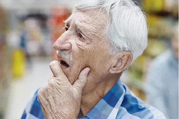 Photo of an elder man looking to his right with his hand on his chin
