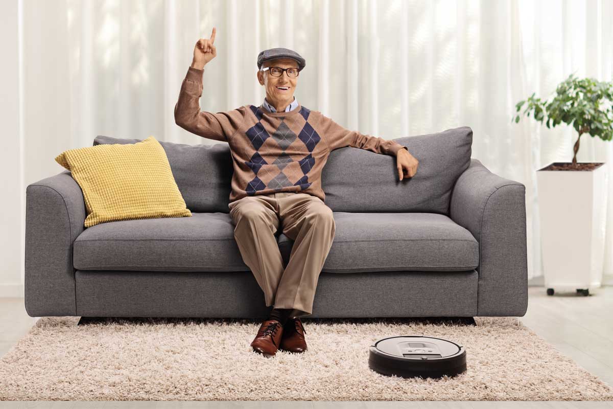 A senior relaxing while a vacuum robot cleans