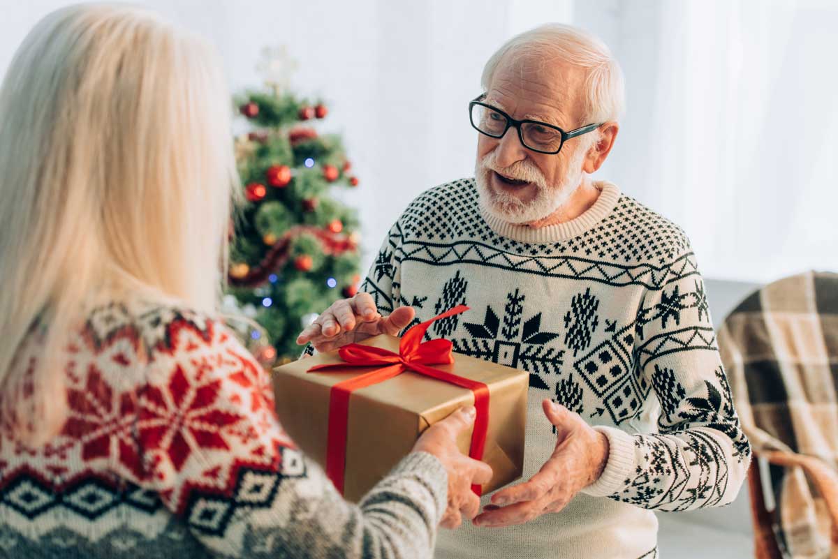 Caregiver giving a Christmas present to a senior