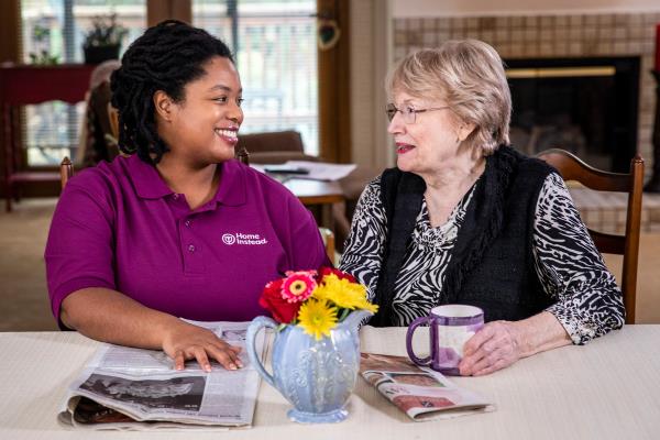 Caregiver and senior woman smiling over coffee