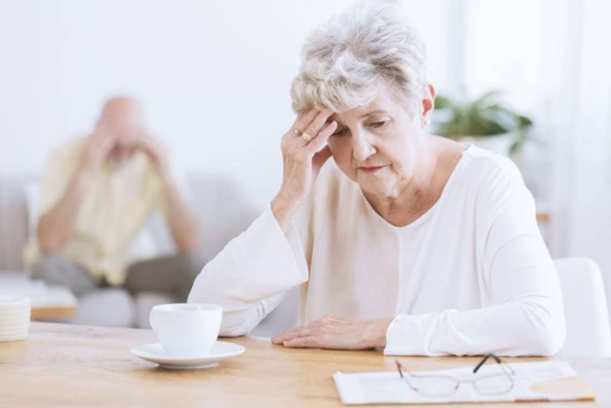 Older woman sitting looking depressed at her cup of coffee