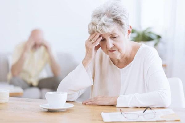 Older woman sitting looking depressed at her cup of coffee