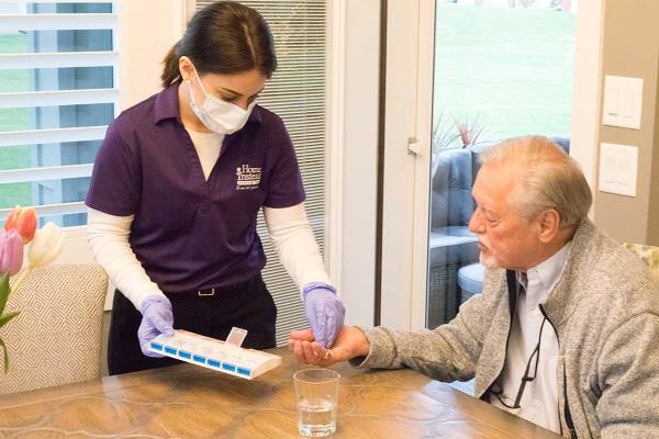 A Home Instead Caregiver reminds a senior of his daily pills
