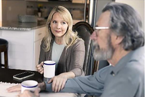 Two people sitting at a kitchen table with coffee