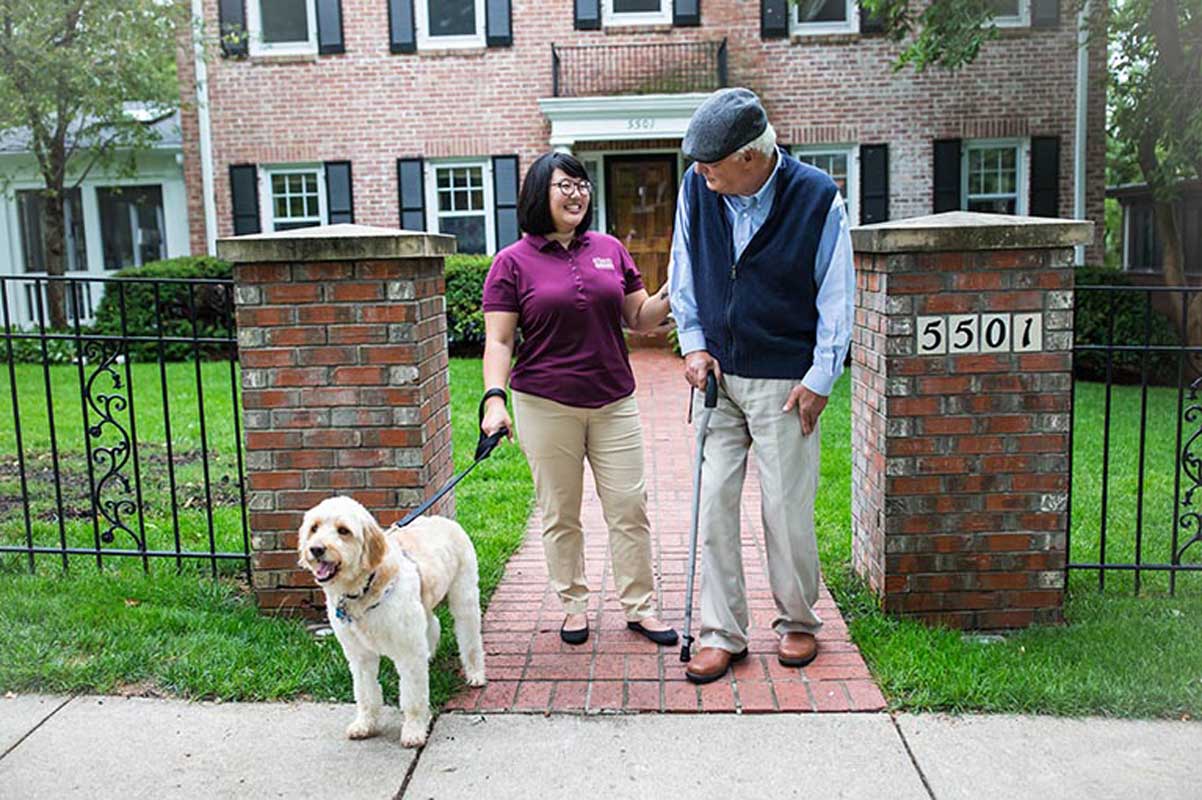 caregiver and senior walking the dog