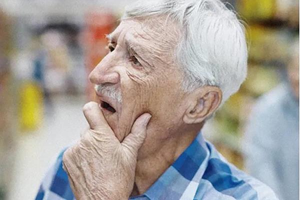 Photo of older man looking off into the distances with his hand on his chin