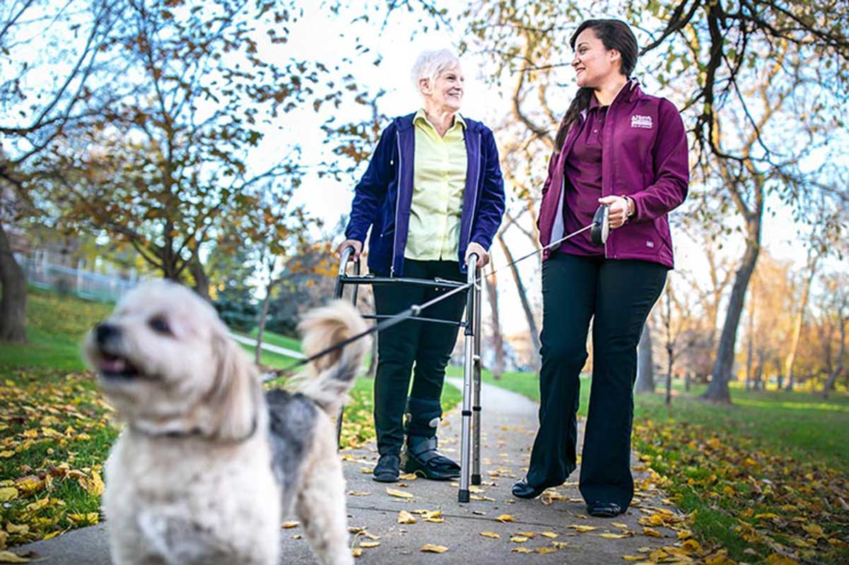 A Senior and a Home Instead Caregiver taking the pet for a walk 