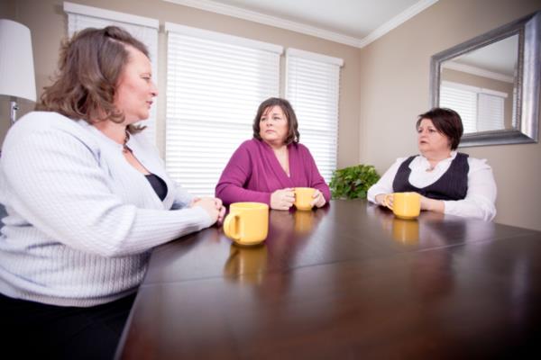 Three daughters sit at kitchen table and talk about care for aging parents