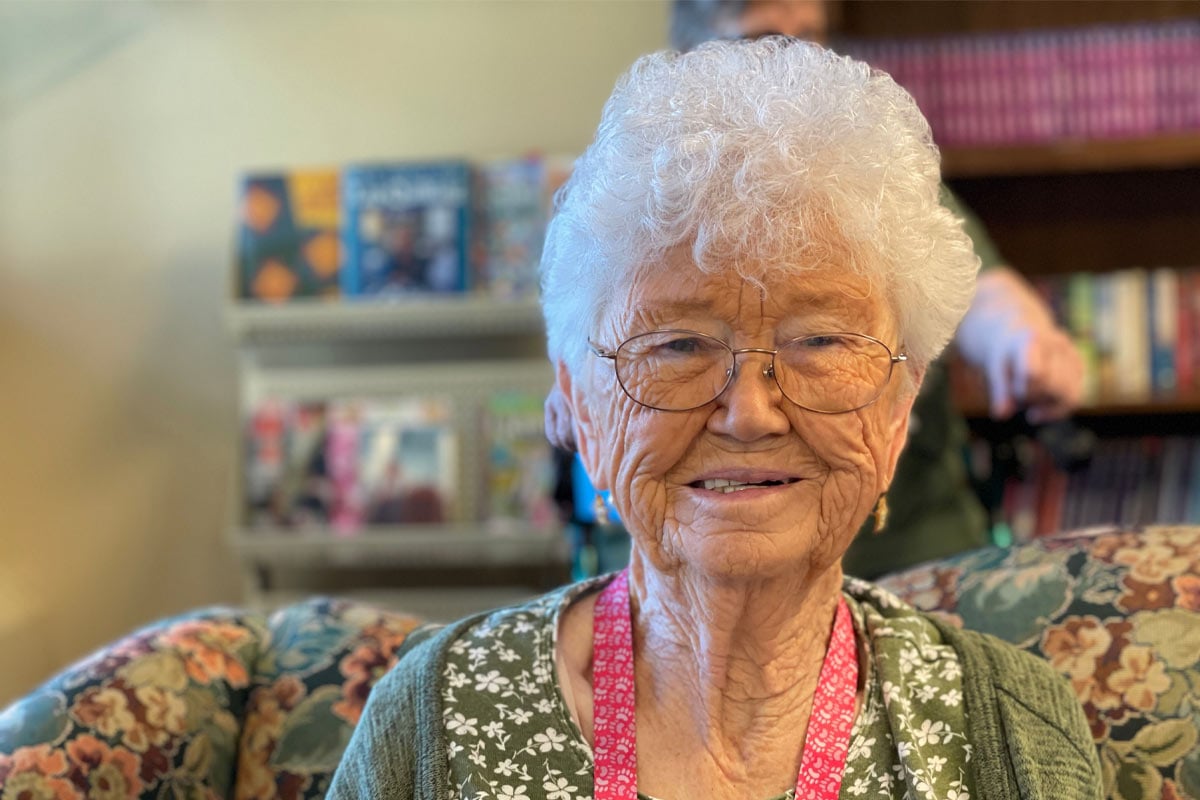 Elderly woman smiling while sitting on sofa