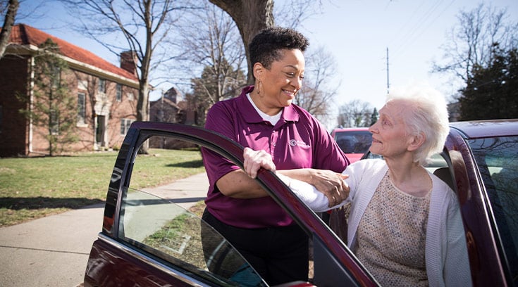Caregiver helping senior into car