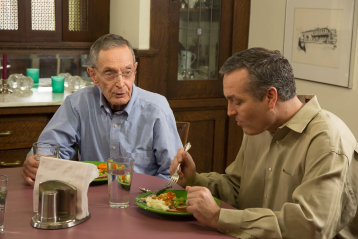 Senior having a conversation with their son at the dinner table