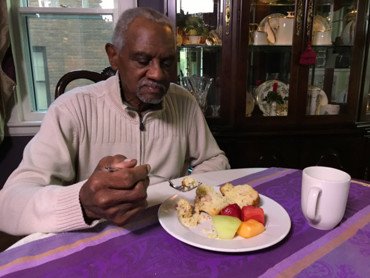 Aging man sitting at dining room table eating healthy meal.