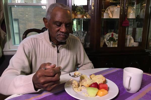 Aging man sitting at dining room table eating healthy meal.