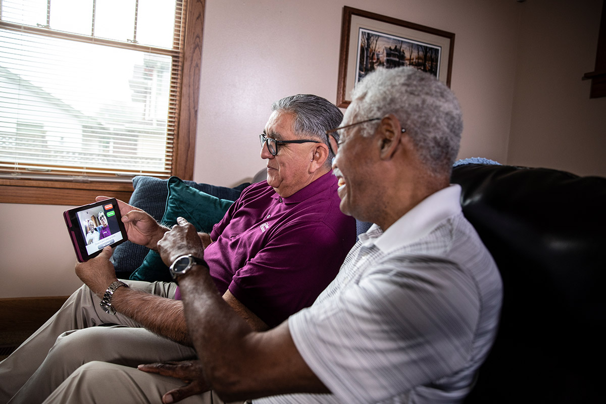 Home Instead Caregiver helps senior man with video conference call at home using tablet