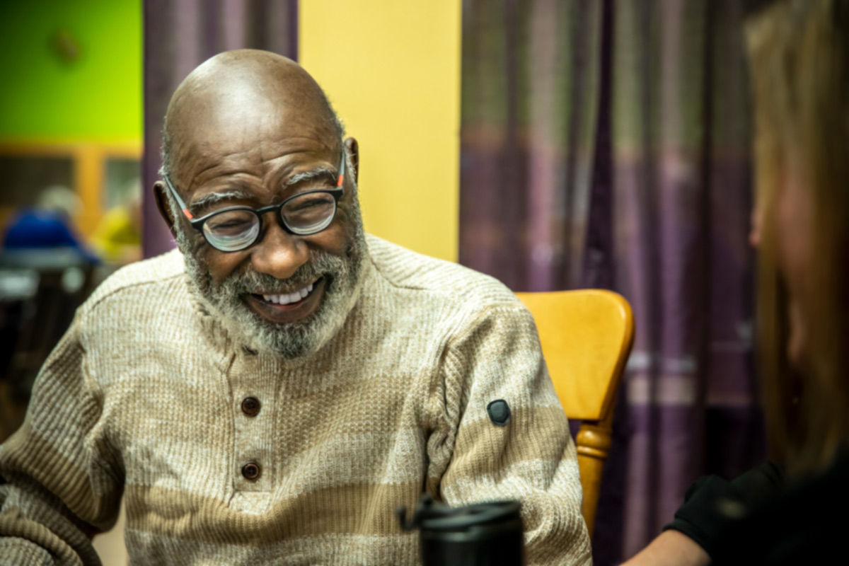 Senior man laughs while sitting at table in home