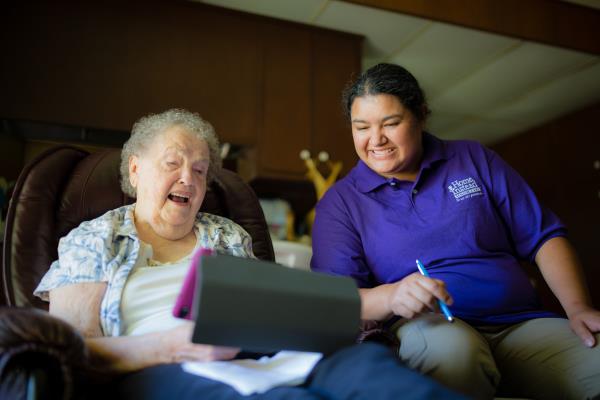 Home Instead Caregiver helps senior man with video conference call at home using tablet