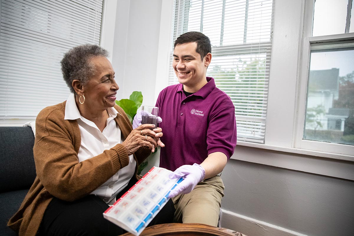 Home Instead Caregiver provides senior woman medication and water