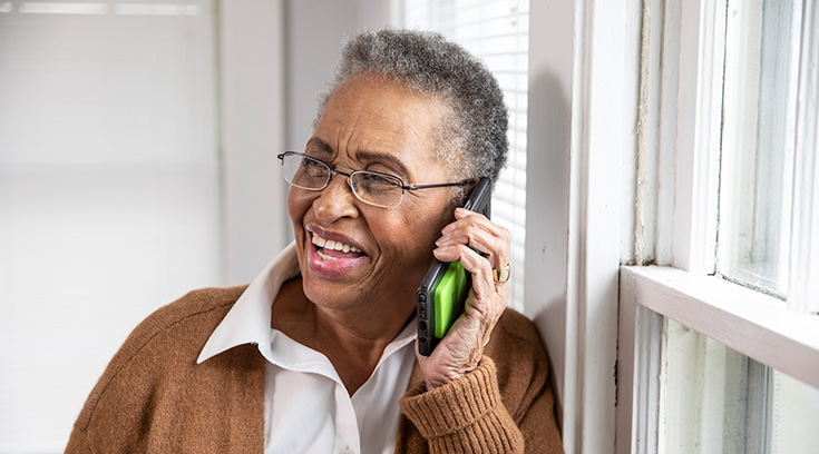 Senior woman smiles while talking on mobile phone at home