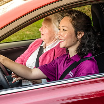 Home Instead Caregiver drives a senior in a car.